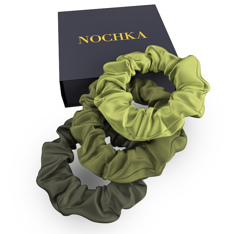 May include: Three green satin scrunchies, stacked on top of each other, with the top scrunchie partially covering the bottom two. The scrunchies are on top of a black box with the word "NOCHKA" printed in gold letters.