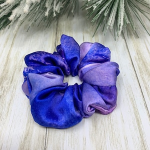 May include: A purple and blue tie-dye scrunchie made of satin.