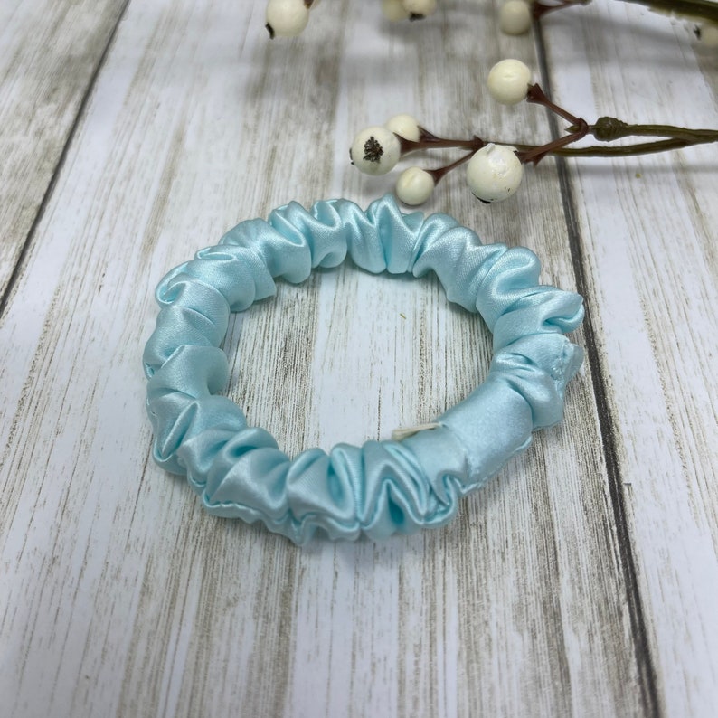 K&ouml;nnte beinhalten: Ein hellblauer Satin-Haargummi.