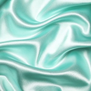 May include: A smooth, flowing piece of fabric in a light aqua color. The fabric is draped and folded, creating soft, gentle curves.