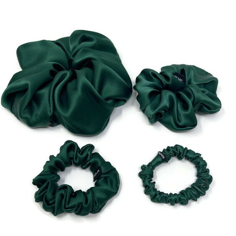May include: Set of four green satin scrunchies. The largest scrunchie is a large, loose bun-shaped scrunchie. The other three scrunchies are smaller and are in the shape of a circle.