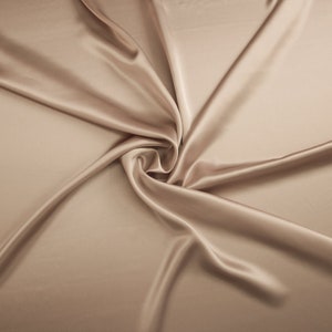 May include: A smooth, luxurious, light brown satin fabric draped in a swirling pattern.