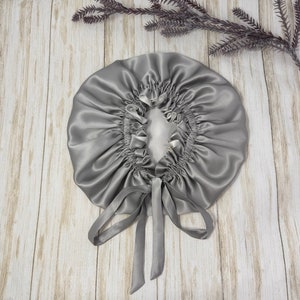 May include: A gray satin sleep cap with a gathered top and a long, tied ribbon.