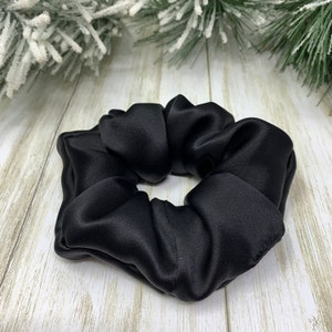 K&ouml;nnte beinhalten: Ein schwarzes Satin-Haargummi.