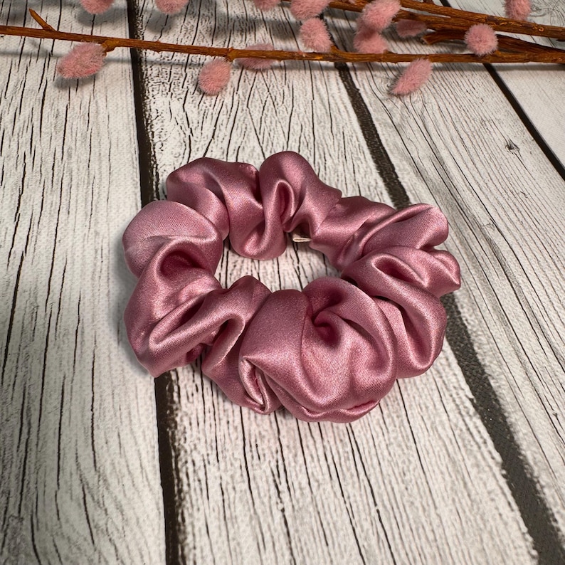 May include: A dusty rose colored scrunchie made of satin.