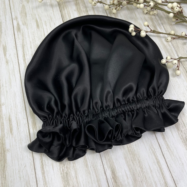 May include: Black satin sleep cap with a ruffled edge. The cap is designed to protect hair from breakage and frizz.