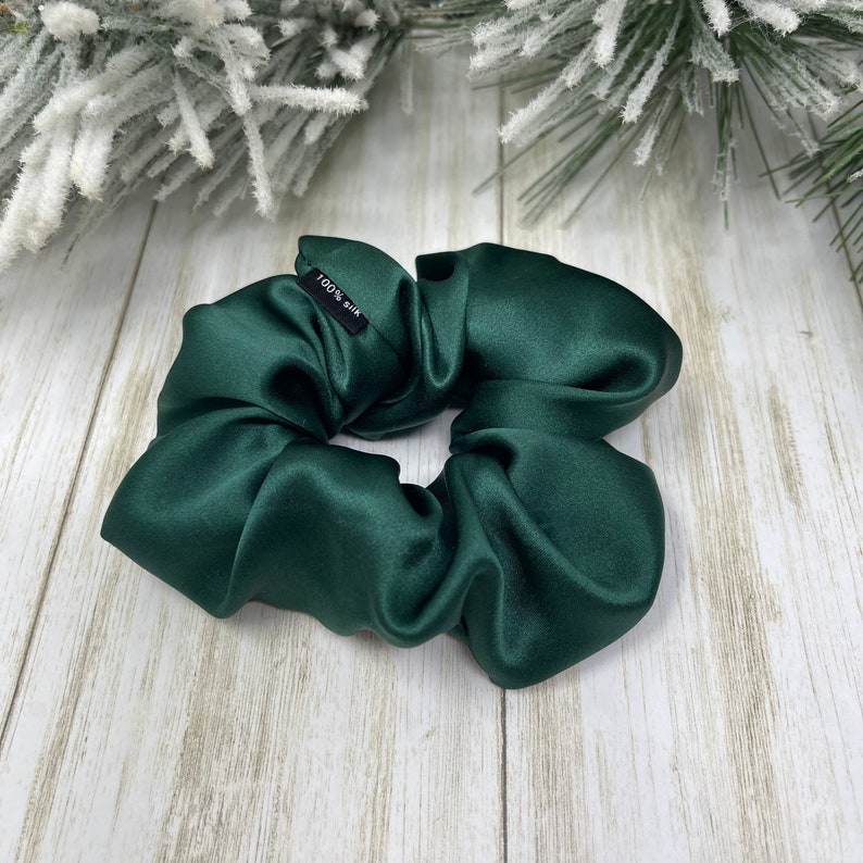 May include: A dark green satin scrunchie with a black tag that reads "100% Silk".
