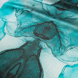 May include: Abstract teal and black watercolor design on a white fabric. The design features swirling, flowing lines and shapes.