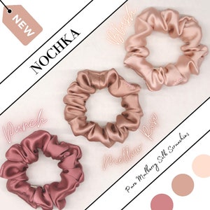 May include: Three silk scrunchies in different shades of pink: blush, mellow rose, and punch. The scrunchies are made of pure mulberry silk and are labeled with the brand name "NOCHKA".
