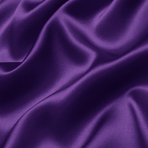 Pode incluir: Um tecido de cetim roxo suave e luxuoso com dobras suaves e fluidas.
