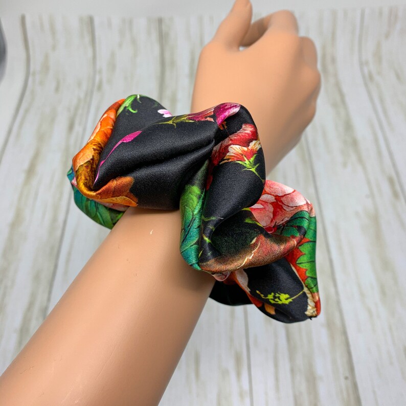 May include: A black and floral patterned scrunchie made of silk.