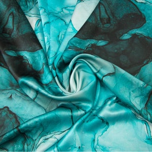 May include: Teal blue silk fabric with a swirling abstract pattern. The fabric has a soft, flowing texture.