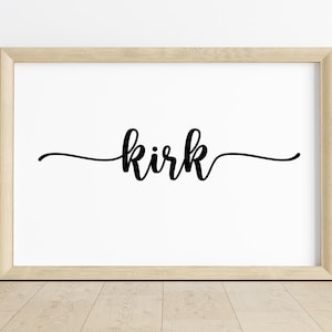 Pode incluir: Uma impressão emoldurada com o nome "Kirk" em elegante escrita preta. A palavra está centrada em um fundo branco, emoldurada por uma moldura de madeira clara. A obra de arte é exibida em um piso de madeira clara.