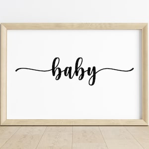Pode incluir: Uma impressão emoldurada com a palavra "baby" em elegante escrita preta. A palavra está centrada em um fundo branco, emoldurada por uma moldura de madeira clara. A impressão é exibida em um piso de madeira contra uma parede branca.