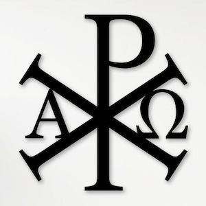 Op de afbeelding: Zwart Chi Rho-symbool met Alfa- en Omega-letters. Het symbool wordt weergegeven tegen een witte achtergrond, met een houten oppervlak op de voorgrond. Decoratieve planten staan aan weerszijden.