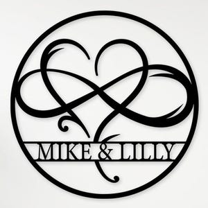 Könnte beinhalten: Schwarze Metall-Wandkunst mit einem Unendlichkeitszeichen in Herzform, das sich in einem Kreis befindet. Die Namen "MIKE & LILLY" sind darunter abgebildet. Die Worte "Custom Order" befinden sich in der oberen linken Ecke.