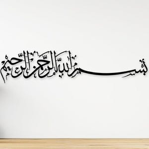 Op de afbeelding: Zwarte Arabische kalligrafie wandkunst. Het kunstwerk toont elegant schrift, waarschijnlijk een religieuze zin, tegen een witte achtergrond. Het ontwerp is een decoratief stuk voor woondecoratie en voegt een vleugje culturele kunst toe.