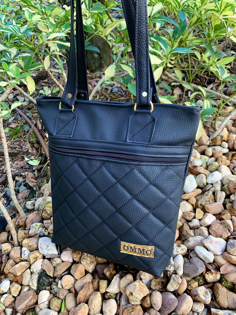 May include: Black quilted tote bag with gold hardware and a gold label that says "OMMO".