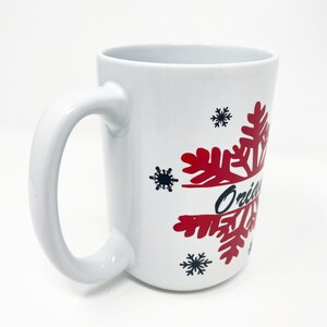 May include: White ceramic mug with a red snowflake design and the word "Original" in black lettering.