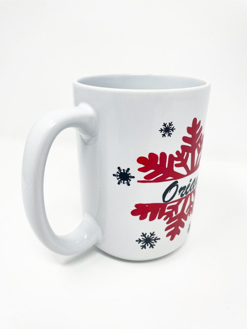 May include: White ceramic mug with a red snowflake design and the word "Original" in black lettering.