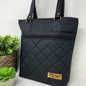 May include: Black quilted tote bag with gold hardware and a gold label that says "OMMO".