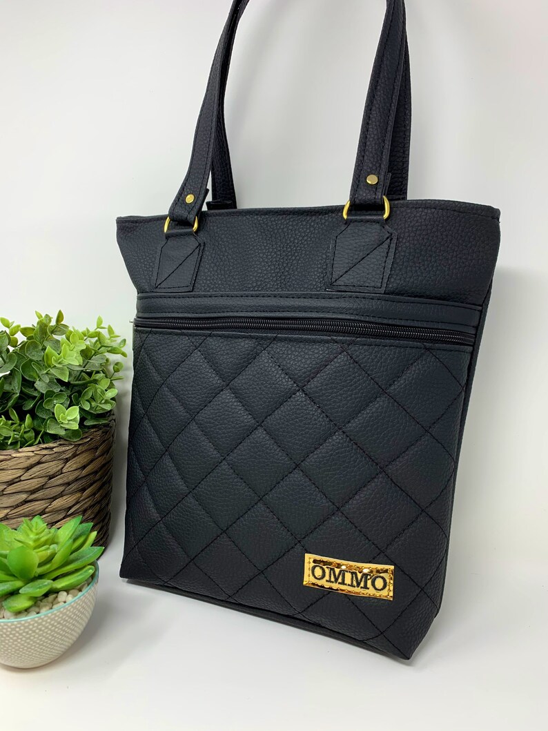May include: Black quilted tote bag with gold hardware and a gold label that says "OMMO".