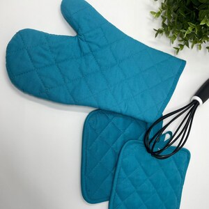 May include: Teal quilted oven mitts and pot holders. The mitts have a quilted design and are perfect for protecting your hands from heat. The pot holders are also quilted and can be used to protect your hands from hot dishes.