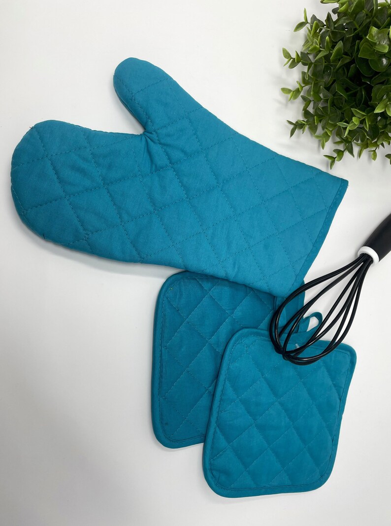 May include: Teal quilted oven mitts and pot holders. The mitts have a quilted design and are perfect for protecting your hands from heat. The pot holders are also quilted and can be used to protect your hands from hot dishes.