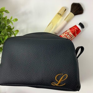 May include: Black leather zippered makeup bag with a gold embroidered letter L.