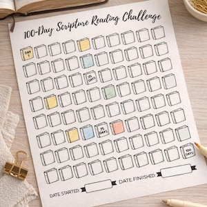 Op de afbeelding: Een wit papier met de tekst "100-Day Scripture Reading Challenge" en een raster van boekcontouren. Sommige vakjes zijn gekleurd. Bevat ruimte voor start- en einddata, met stiften en een gouden paperclip.