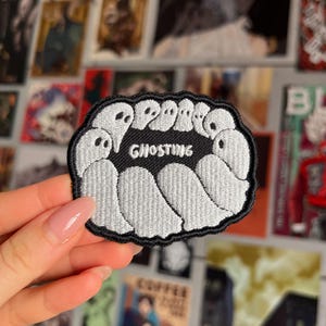 Op de afbeelding: Een geborduurde patch in zwart en wit met een cirkel van witte geesten rond het woord "Ghosting".
