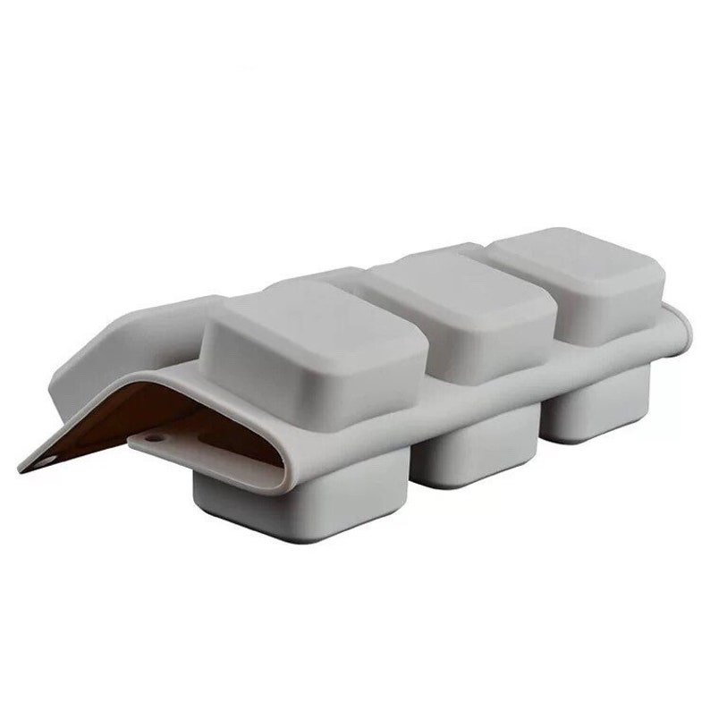 May include: Gray silicone mold with four square cavities for making chocolate or other treats.