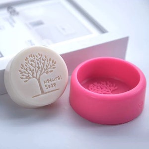 May include: A pink silicone soap mould with a tree design. The mould is empty and ready to be used to make soap. The mould is round and has a diameter of approximately 7.5 cm.