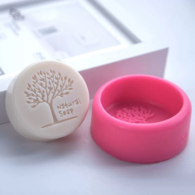 May include: A pink silicone soap mould with a tree design. The mould is empty and ready to be used to make soap. The mould is round and has a diameter of approximately 7.5 cm.