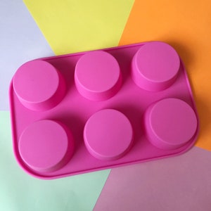 May include: Pink silicone mould with six round cavities for making small cakes or other treats.