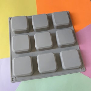 May include: Gray silicone mold with nine square cavities for making soap or other crafts.