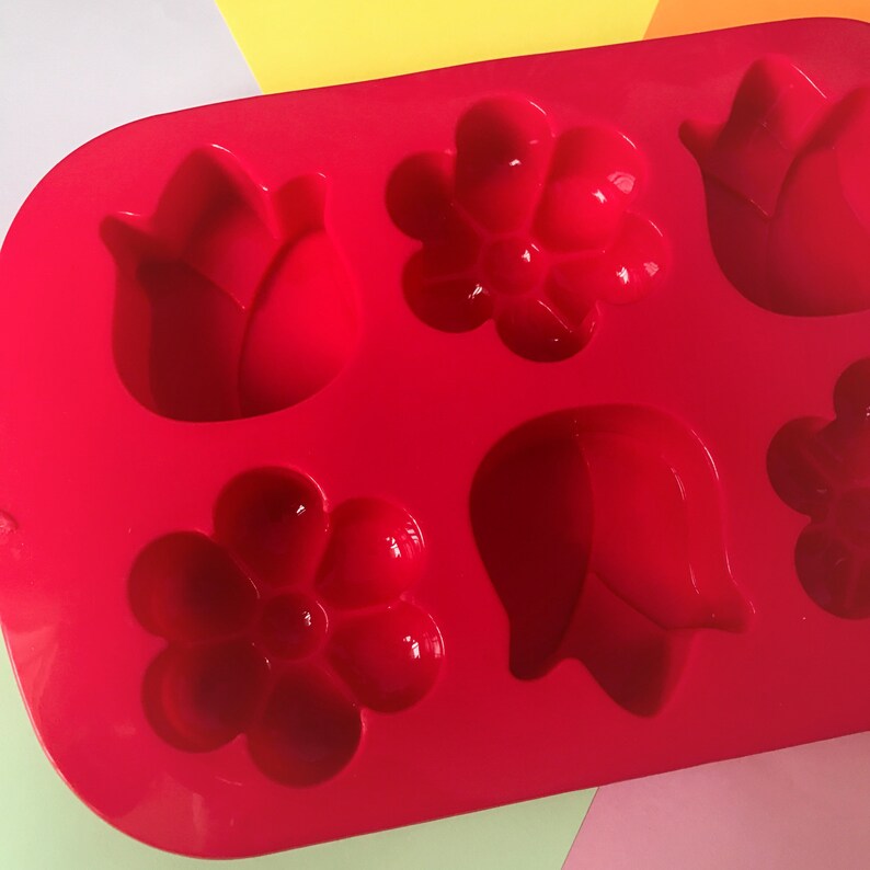 May include: Red silicone mold with six cavities shaped like flowers and tulips.