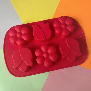 May include: Red silicone baking mold with six cavities shaped like flowers and tulips.
