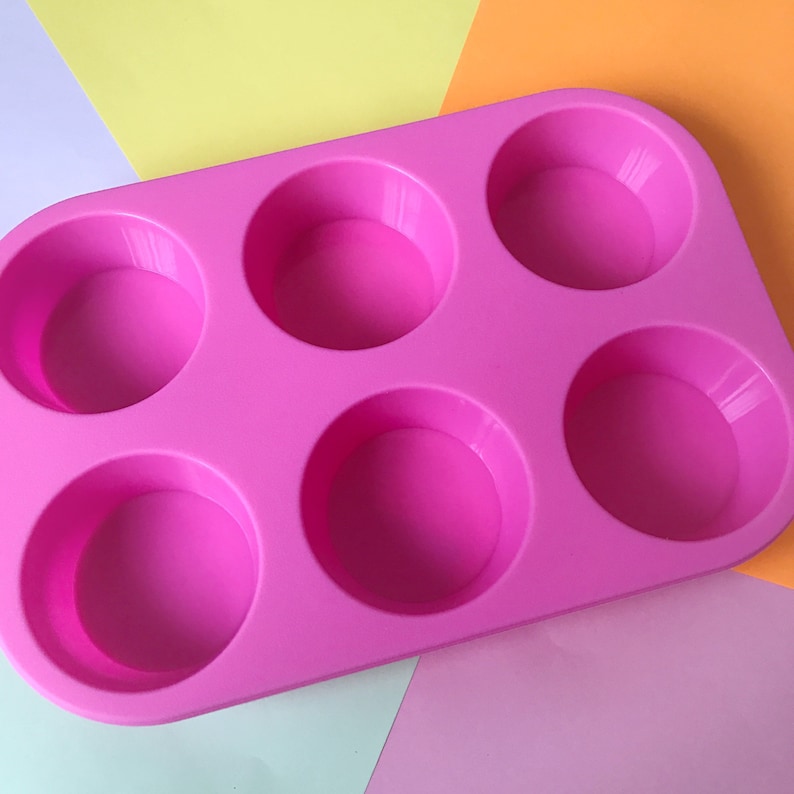 May include: Pink silicone baking mould with six round cavities. The mould is designed for making cupcakes, muffins, or other small treats.