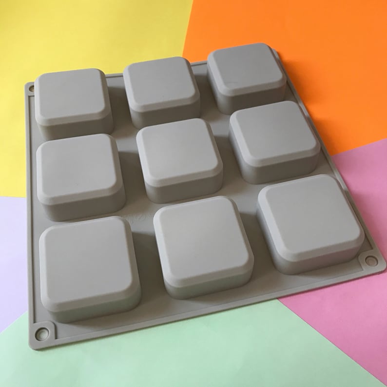May include: A gray silicone mold with 9 square cavities. The mold is designed for making small square soaps or other crafts.