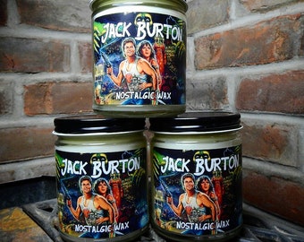 May include: Three glass jars with black lids are stacked. Each jar has a label featuring the movie title "Jack Burton" and the words "Nostalgic Wax". The labels display a movie scene with actors. The jars are on a metal grate.
