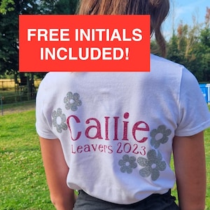 May include: White t-shirt with a pink glitter design that says "Callie Leavers 2023" surrounded by silver glitter flowers. The text "FREE INITIALS INCLUDED!" is in a red box.
