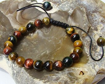 May include: A brown, gold, and black tiger's eye beaded bracelet with a black cord and adjustable clasp. The bracelet is made of round beads and is approximately 8 inches in length.