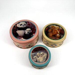 May include: Three round decorative tins with lid. One tin features a panda bear family, another a teddy bear, and the third a family of white bears. The tins have colorful designs and are set against a white background.