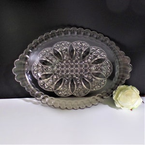 May include: A clear glass oval serving tray with a scalloped edge and a raised, embossed floral design in the center.