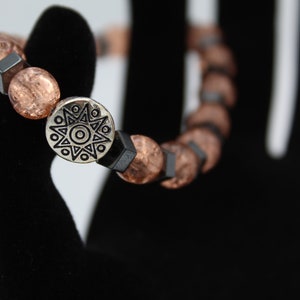 May include: A bracelet with brown and black beads and a silver charm with a star design.