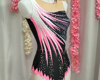 May include: A black leotard with pink, white, and gray geometric designs. The leotard is decorated with rhinestones and has a jagged pink trim.