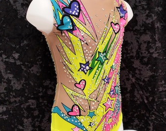 May include: A yellow, pink, blue, and green swimsuit with a lightning bolt and star pattern. The swimsuit is decorated with rhinestones.