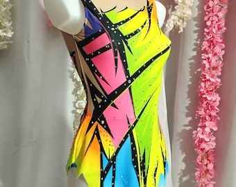 May include: A colorful leotard with a geometric design in shades of yellow, pink, blue, and black. The leotard is decorated with rhinestones and has a jagged hemline.