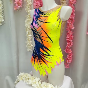 May include: A yellow, pink, orange, and blue leotard with a geometric design and rhinestones. The leotard has a scoop neck and a sleeveless design.